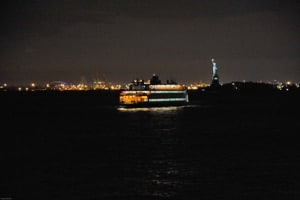 Beleuchtet Fähre in der Nacht, auf dem Weg nach Staten Island, im Hintergrund die Freiheitsstatue
